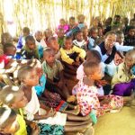 kindergarten students listening to teacher in stick hut in Malawi