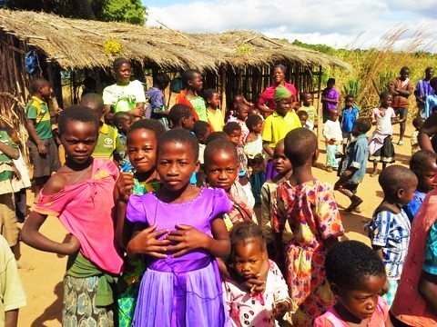 thatched roof and stick walls makeshift kindergarten in Malawi with students smiling